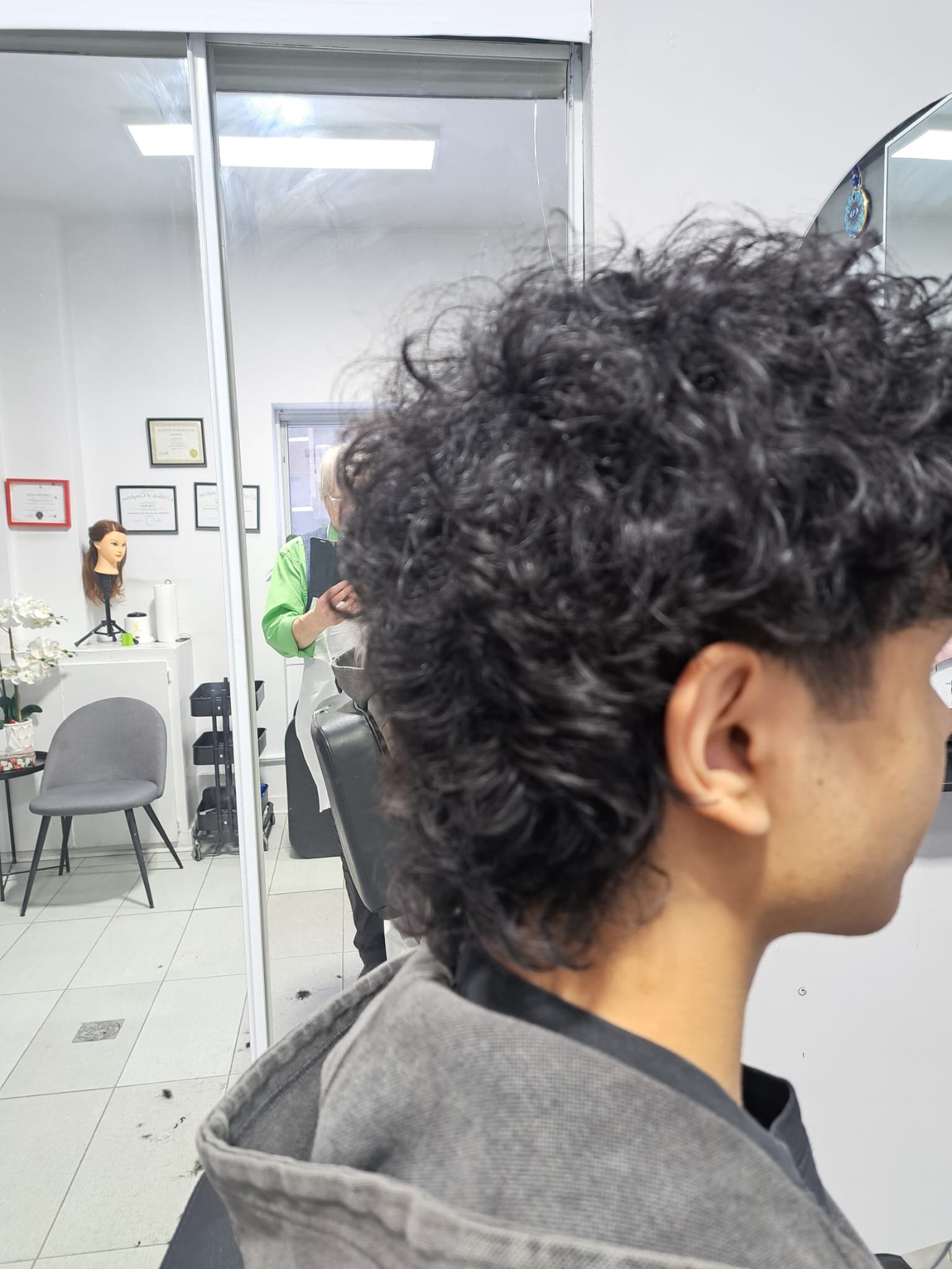 Curly men's fade haircut shown from the side by Konstantin Stylist